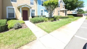 A row of townhouses with a front lawn, a driveway, and a street.
