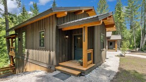 A rustic cabin with a wooden exterior, a front porch, and a gravel driveway. - Sandhill - Luxury Cabin (Flathead County)
