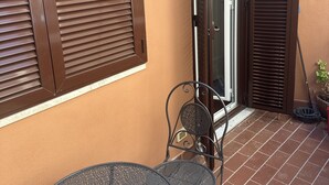 Eine Terrasse mit zwei Metalltischen, einer Wandleuchte und einer Schiebetür.
