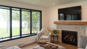 Una sala de estar con chimenea, un ventanal grande y un sillón estampado con motivos florales.