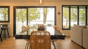 Comedor con una mesa grande, sillas y vistas a árboles a través de amplios ventanales.