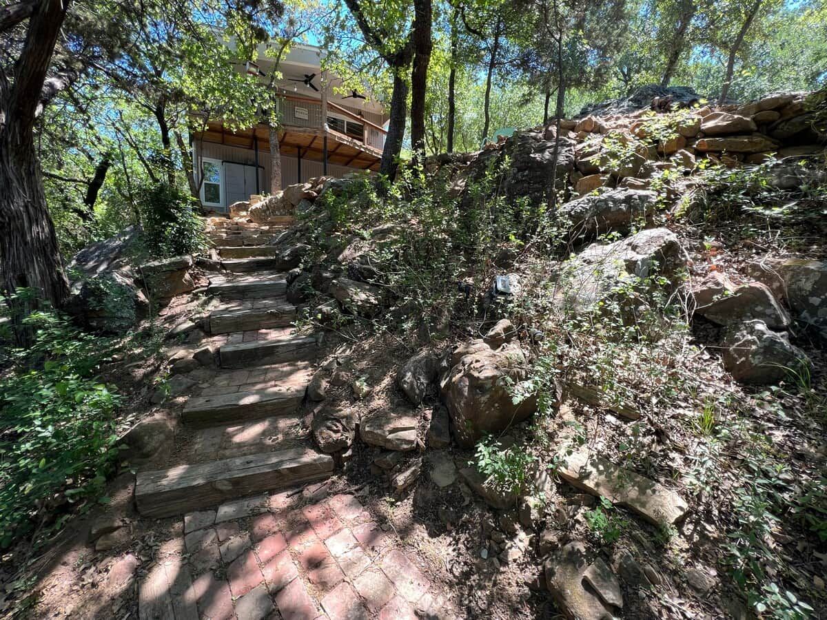 A set of stone steps leading up a rocky slope, surrounded by trees and vegetation.