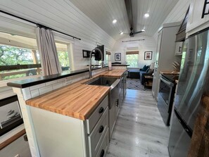 Une cuisine moderne dotée de plans de travail en bois, d’appareils électroménagers en acier inoxydable et d’un îlot central.