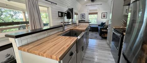 Een moderne keuken met houten aanrechtbladen, roestvrijstalen apparatuur en een centraal kookeiland.