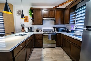 A modern kitchen with dark wooden cabinets, stainless steel appliances, and a white countertop.