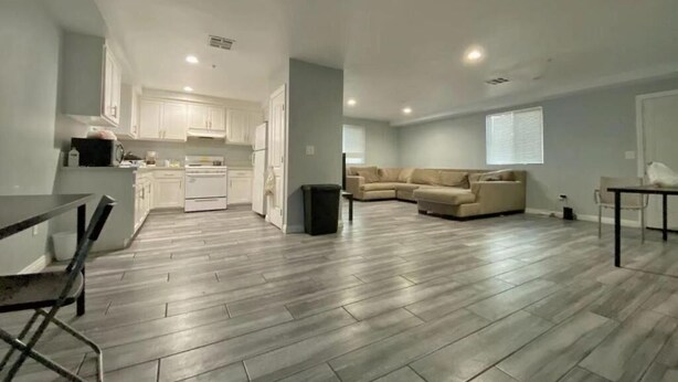 A spacious living area with a kitchen, a dining area, and a seating area with a sofa and chairs. - Modern Hostel (Los Angeles)