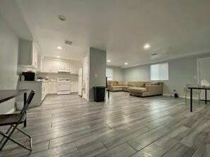 A spacious living area with a kitchen, a dining area, and a seating area with a sofa and chairs. - Modern Hostel (Los Angeles)