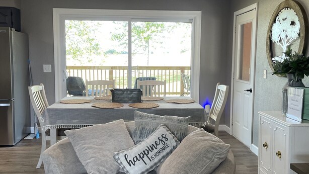 Una sala de estar acogedora con un sofá gris, una mesa de comedor y vistas a una terraza de madera.