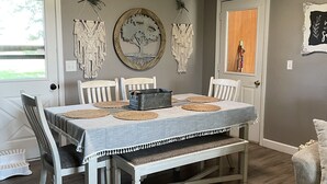 Un comedor con una mesa preparada para cuatro personas, rodeada de sillas y un banco.