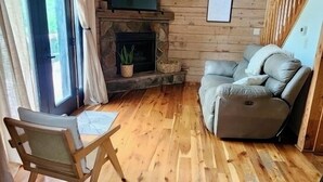 A cozy room with a stone fireplace, wooden ceiling, and a comfortable sofa.