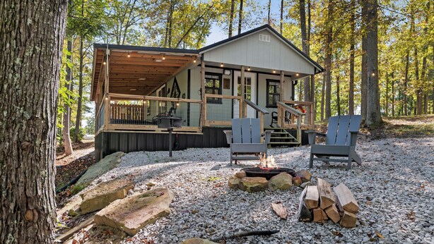 Eine Hütte mit Terrasse, Sitzgelegenheiten im Freien und einer Feuerstelle.