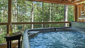Ein Whirlpool mit einer Holzterrasse und Blick auf einen Wald.