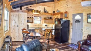Ein Holzblockhaus mit Küche, Essbereich und Sitzgelegenheiten.
