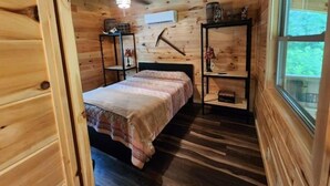 Ein Schlafzimmer einer Holzhütte mit Bett, Regalen und einem Fenster.