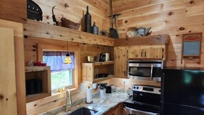 Eine holzgetäfelte Küchenzeile mit Spüle, zwei Herden, einem Kühlschrank sowie diversen Küchengeräten und Utensilien.