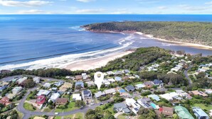 An aerial view of a coastal residential area with houses, roads, and a beach.