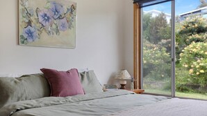 A bedroom with a bed, pillows, a nightstand, a lamp, and a painting.
