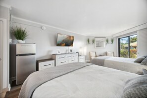 Ein modernes Schlafzimmer mit zwei Betten, einer weißen Kommode, einem Flachbildfernseher und einem Kühlschrank.