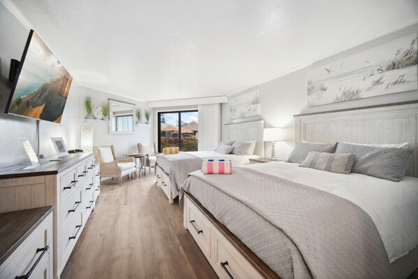 Ein modernes Schlafzimmer mit einem großen Bett, einem Schreibtisch und einem Stuhl. Es gibt ein Fenster mit Bergblick und ein Bild an der Wand.