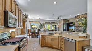 A spacious kitchen with wooden cabinets, a stainless steel dishwasher, and a large island. - Casa Royal Troon- Active 55+ Golf Course Community, Private Home w Pool and Spa! (Indio)