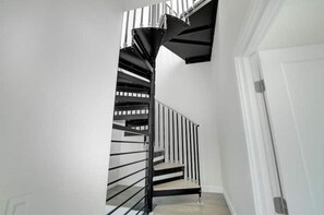 Stunning spiral staircase with a black metal railing leads to an upper level.