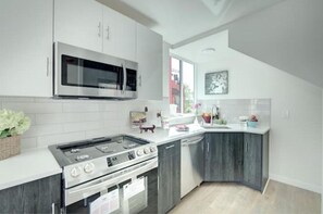 Enjoy cooking in this well-equipped kitchen with a gas stove, microwave, and stainless steel range hood.