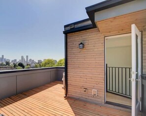 Enjoy the city view from this balcony with a glass door leading to an interior space.