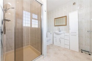 Une salle de bain moderne avec une douche à parois de verre, un lavabo blanc et un meuble-vasque avec des placards.