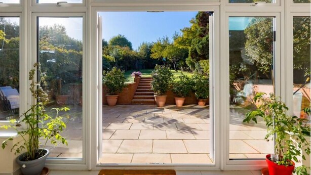 A view through a large window into a garden with a stone staircase leading to a wooden deck.