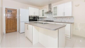 A modern kitchen with white cabinetry, a central island, a built-in oven, and a stainless steel range hood.