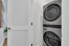A laundry room with two front-loading washing machines and a closed white door.