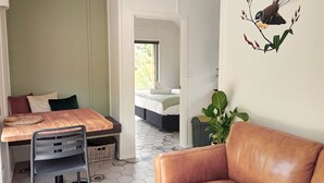 Quarto com uma mesa de jantar de madeira, uma cadeira cinza, um sofá de couro marrom e uma planta verde grande.