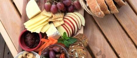 Une table en bois sur laquelle est disposée une planche de charcuterie, avec une variété de viandes, de fromages, de fruits, de noix et de pain.