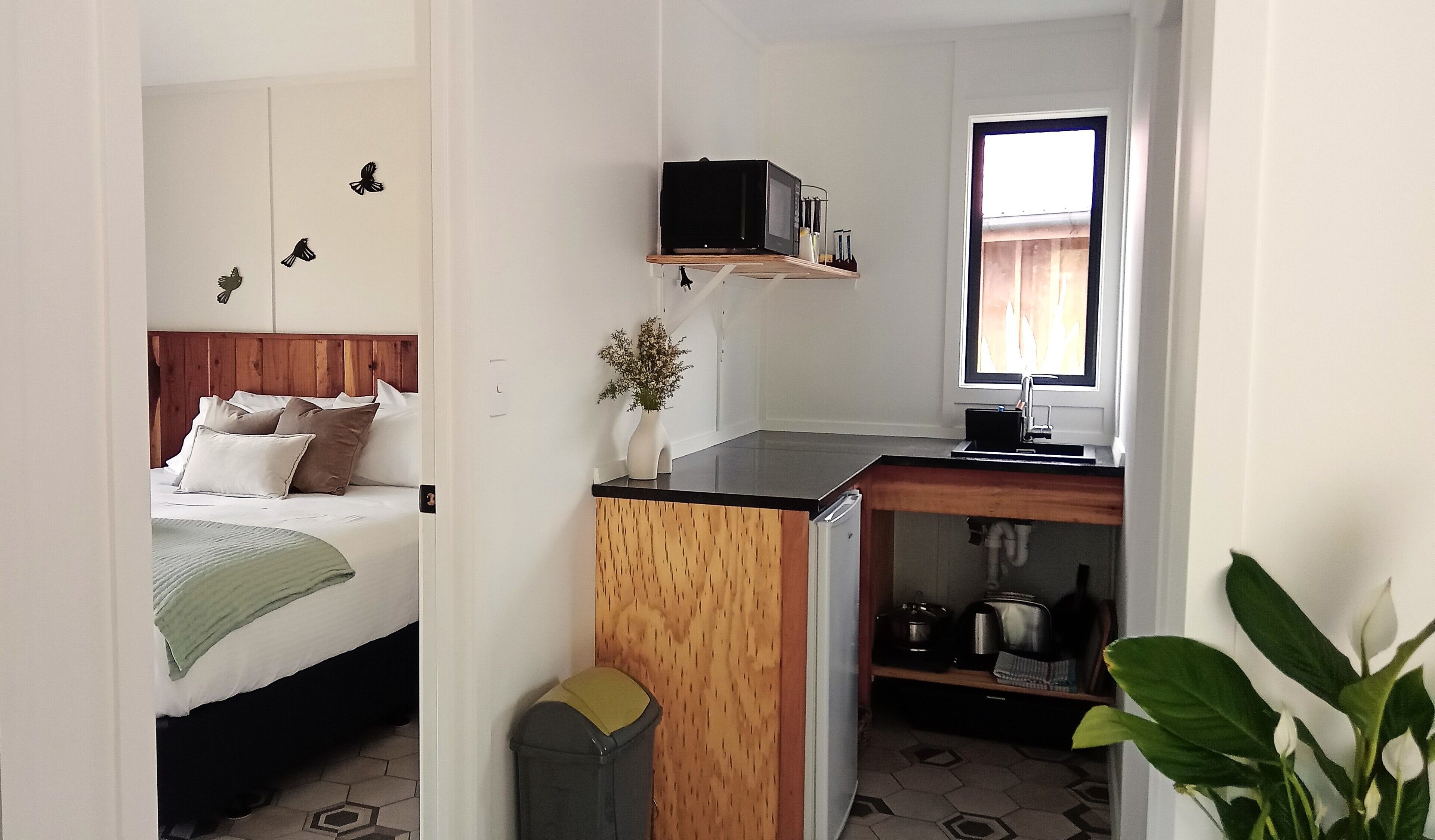 A compact room with a bed, a small kitchenette, and a window.
