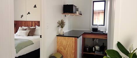 A compact room with a bed, a small kitchenette, and a window.