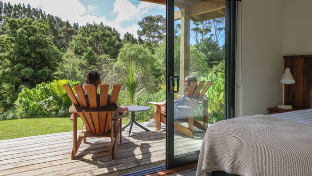 Quarto com porta de vidro deslizante que dá para um terraço com mobiliário ao ar livre.