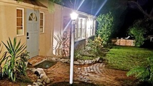 Een huis met een met baksteen bestraat pad dat naar een deur leidt, omringd door groen en een kleine tuin.