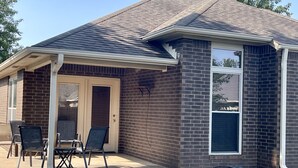 Une maison dotée d’un patio couvert, d’une façade en briques et d’une grande fenêtre.