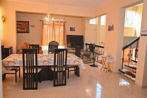 Enjoy dining and relaxation in this inviting space with a large table for four, comfortable seating, and a cozy staircase.