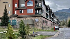 Un hotel de varios pisos con fachada de piedra, balcones y vistas a las montañas.