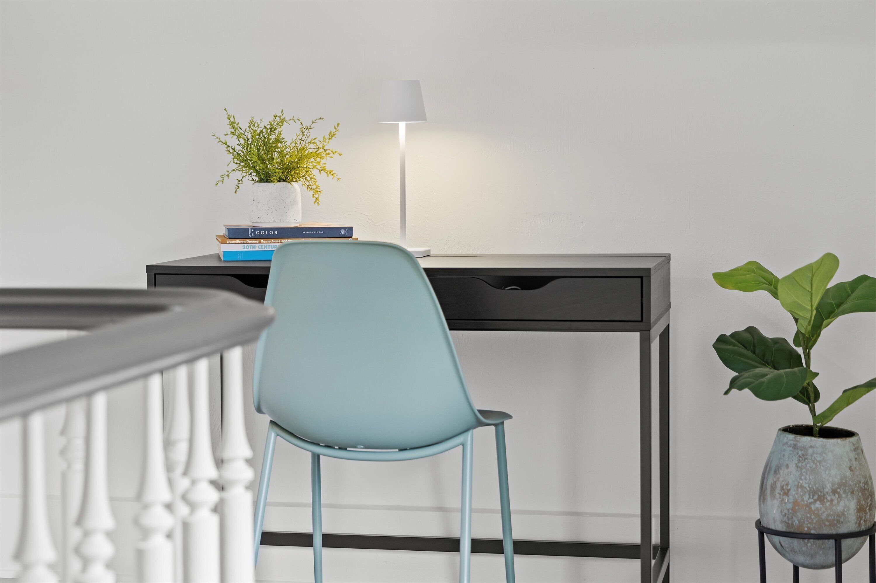 Ein moderner Schreibtisch mit einer Lampe, einem blauen Stuhl und einem Blumentopf.