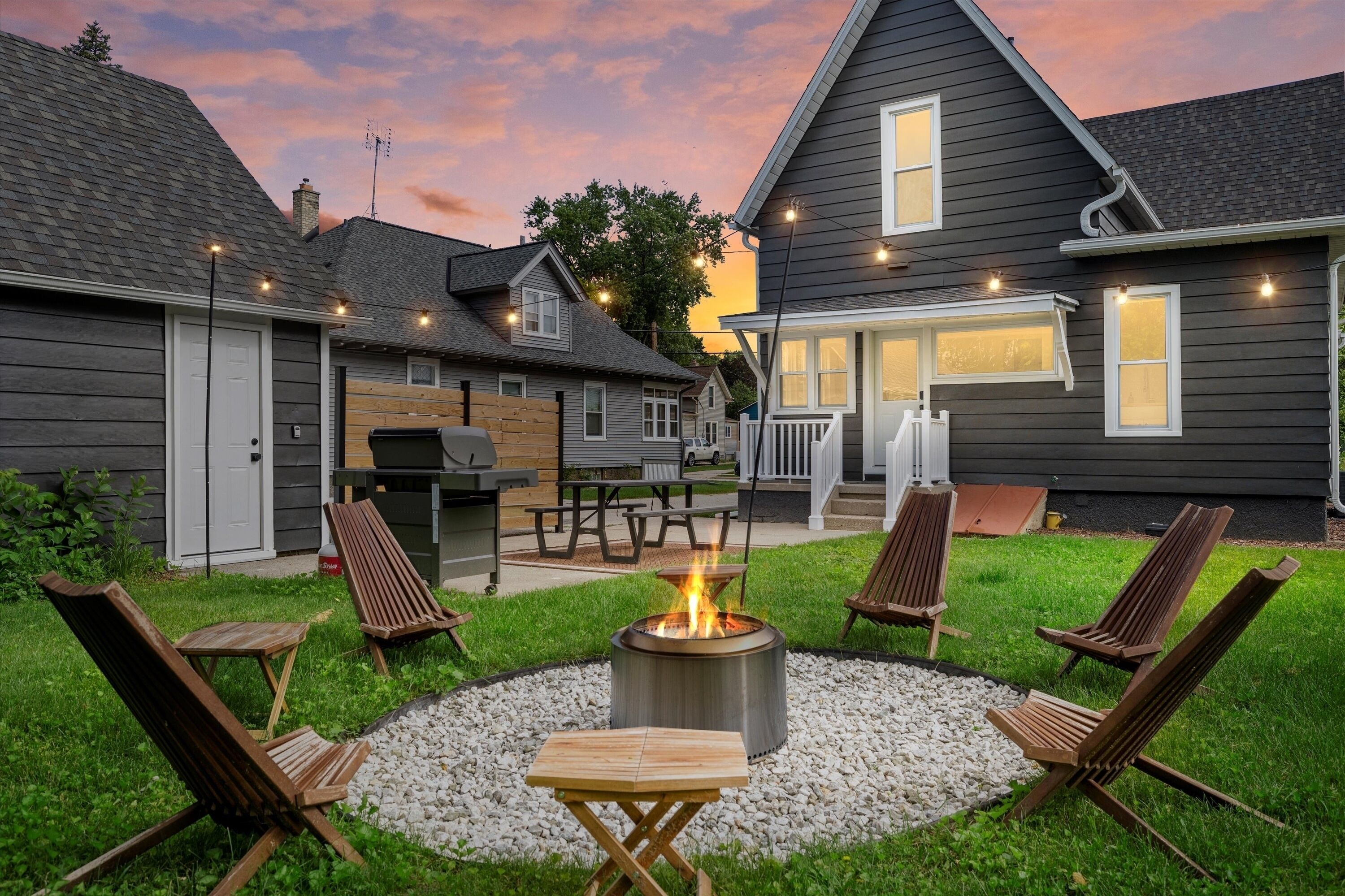 A backyard with a fire pit, outdoor seating, and a barbecue area.