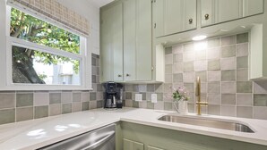 Een keuken met een vaatwasser, een koffiezetapparaat en een gootsteen met een gouden kraan.