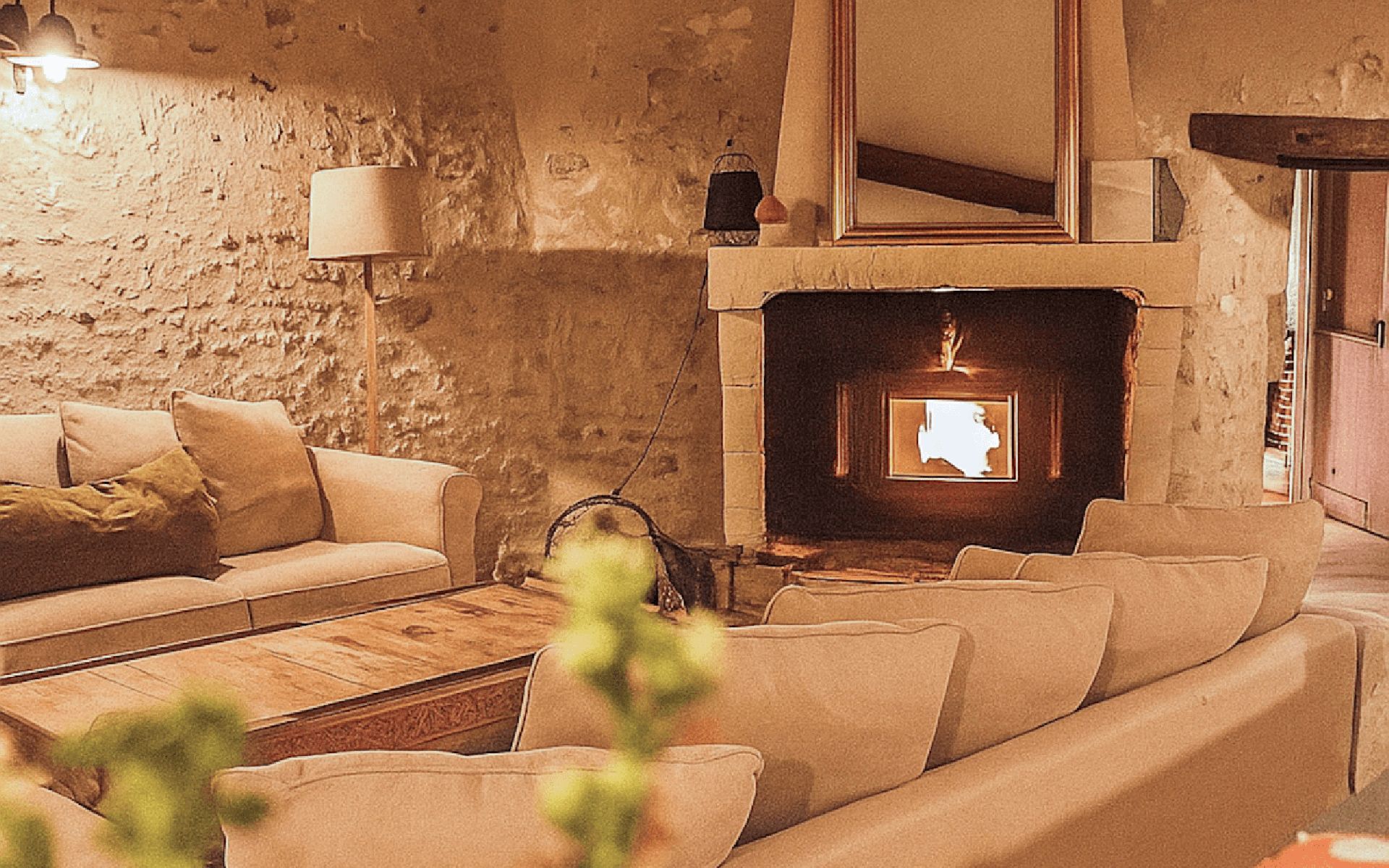 Una sala de estar acogedora con pared de piedra, chimenea, sofá y mesa de centro.