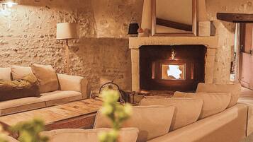 Una sala de estar acogedora con pared de piedra, chimenea, sofá y mesa de centro.