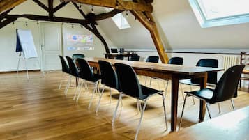 A conference room with a wooden table, black chairs, a whiteboard, and a projector screen.