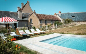 A swimming pool with lounge chairs and a red and white striped umbrella. - The Domaine de la Chambaudière is a former monastery steeped in history, nestled (Molineuf)