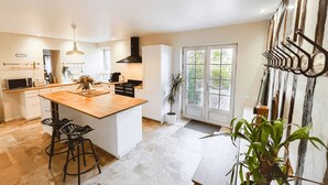 Una cocina moderna con una isla central, taburetes de bar, una estufa y un ventanal grande.