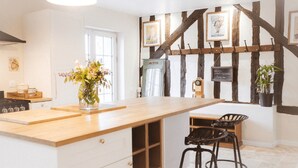 Una cocina con una isla de madera, taburetes de bar, una radio antigua y vigas a la vista en la pared.