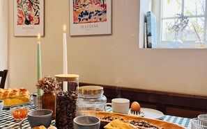 Een ontbijtsetting met een gedekte tafel voor twee personen, met brood, koffie en een kaars.